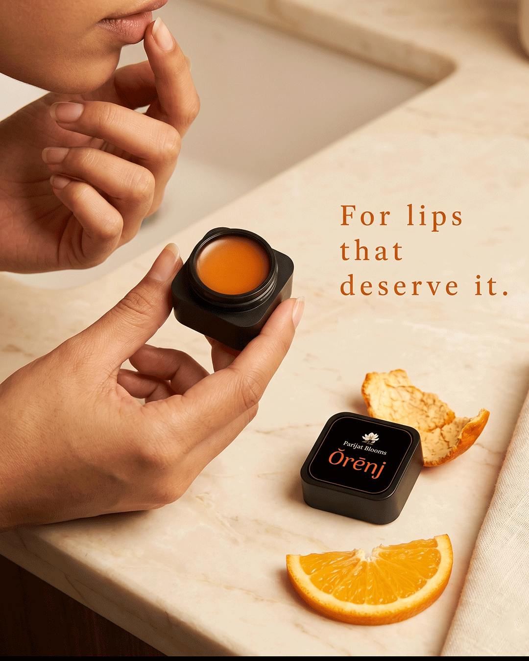 Orenj Orange Lip Balm Ayurvedic ritual lip balm in use — hand holding lip balm Parijat Blooms India